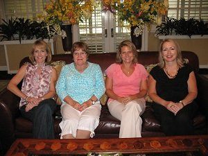 Four women are posing for a picture while sitting on a couch