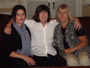 Three women are posing for a picture while sitting on a couch