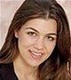 A close up of a woman 's face with long hair smiling.