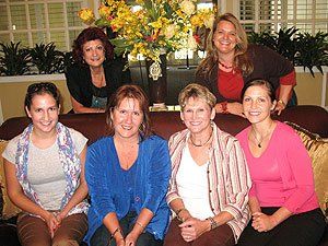 A group of women are posing for a picture while sitting on a couch.