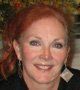 A woman with red hair and earrings is smiling for the camera.