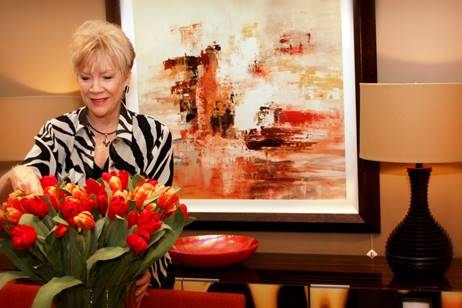 A woman is arranging flowers in front of a painting