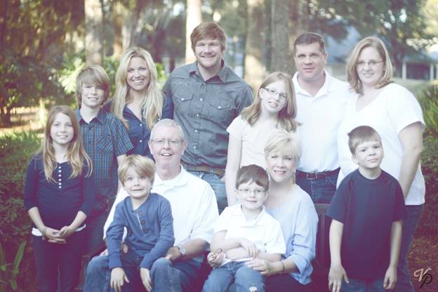 A large family is posing for a picture together in a park.