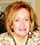 A woman wearing a necklace and earrings is smiling for the camera.