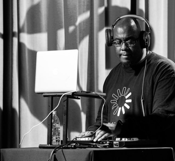 DJ with headphones, laptop, and turntable. Black and white photo, indoors, performing.