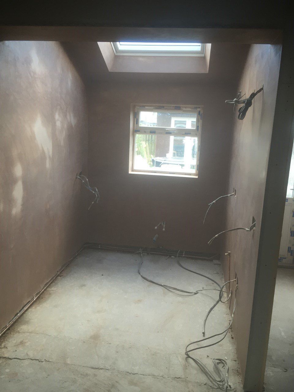 An empty room with a window and a skylight in the ceiling.