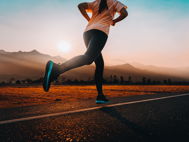 Woman enjoys running outside with beautiful summer evening in the countryside.