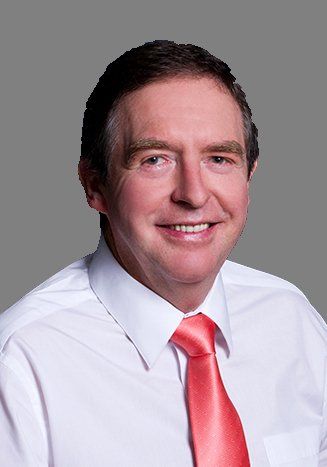 A man in a white shirt and red tie is smiling for the camera.