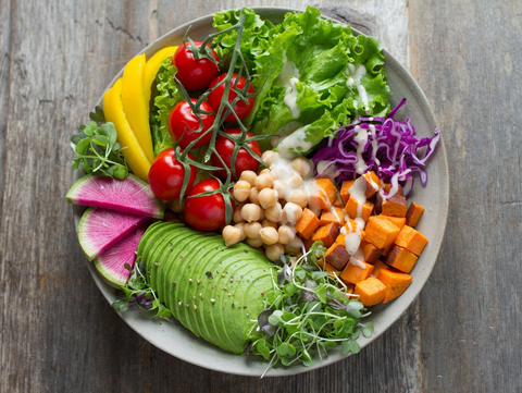 Colorful salad bowl with vegetables on a wooden table.
