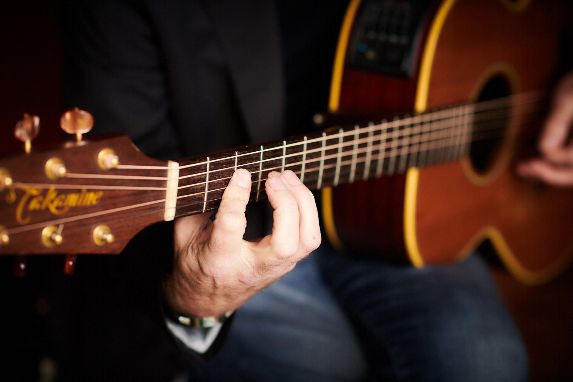 A guitarist's hands playing an acoustic guitar