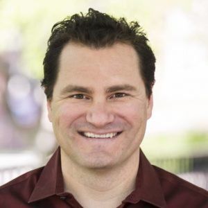 A man in a red shirt is smiling for the camera.
