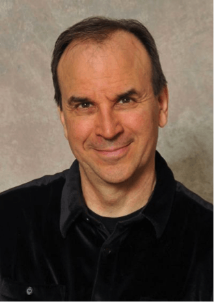 A man wearing a black shirt and a black jacket smiles for the camera