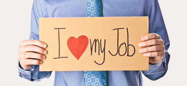 A man in a shirt and tie holds a sign reading 'I love my job'
