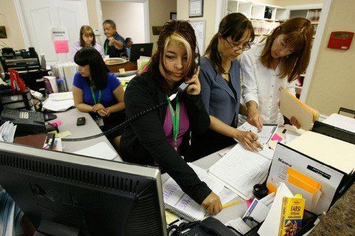 A busy group of medical staff answer calls, organize the office, and discuss patients