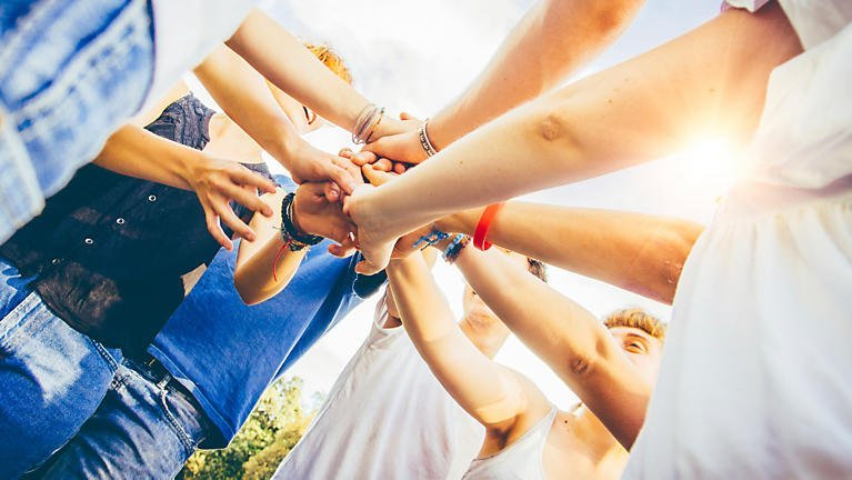 Volunteers' hands pile together in comradery 