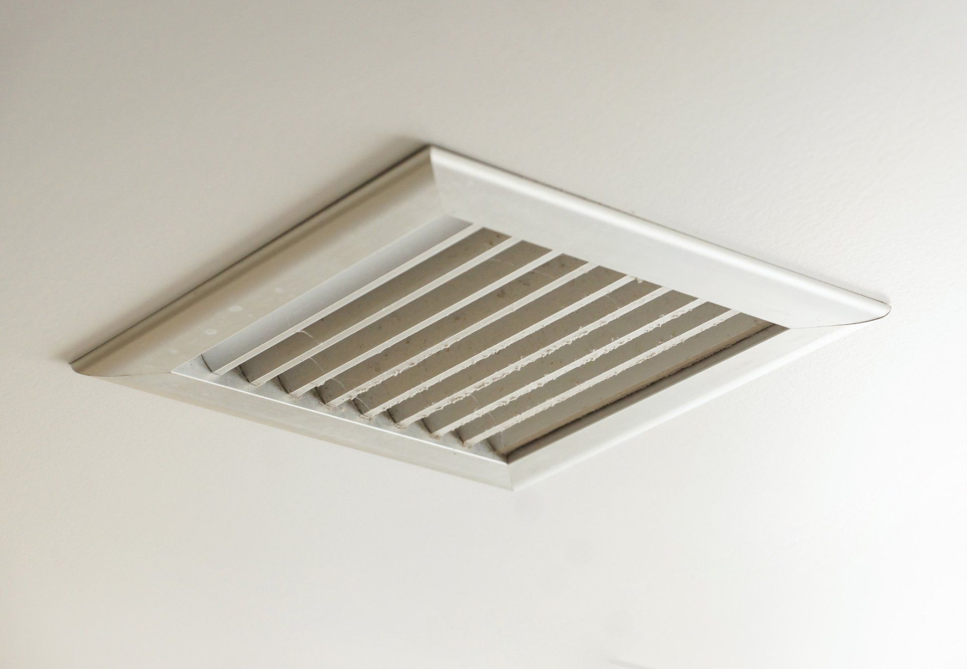 White ceiling air vent with angled slats.