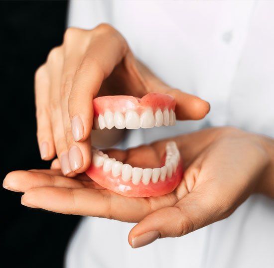 Dentist Holding Dentures — Louisville, OH — Louisville Dental Clinic Dentist Holding Dentures — Louisville, OH — Louisville Dental Clinic