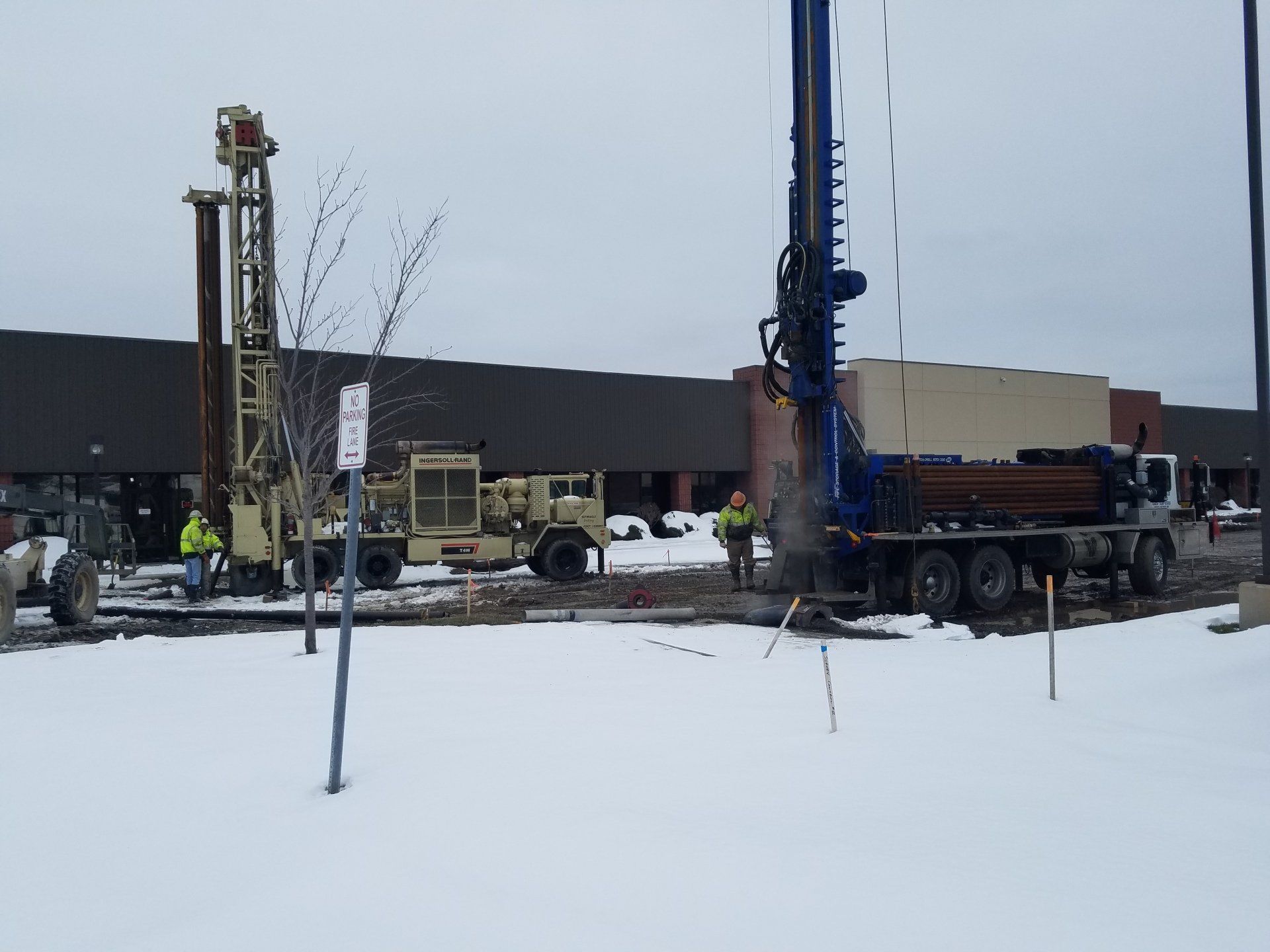 a drill is being used to dig a hole in the snow in front of a building .