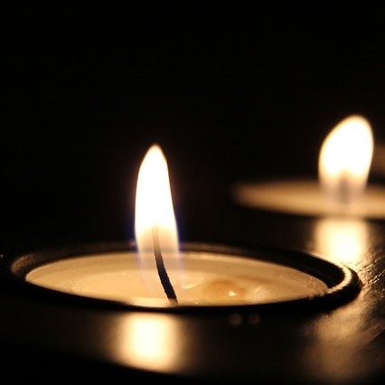 Twee brandende kaarsen in het donker, een warme gloed verlicht de omgeving.