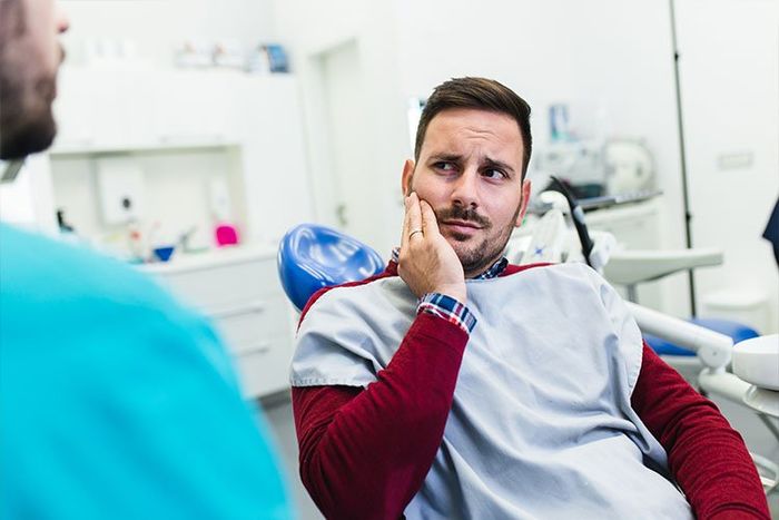 Young man holding his jaw in the dental chair at Union Dental