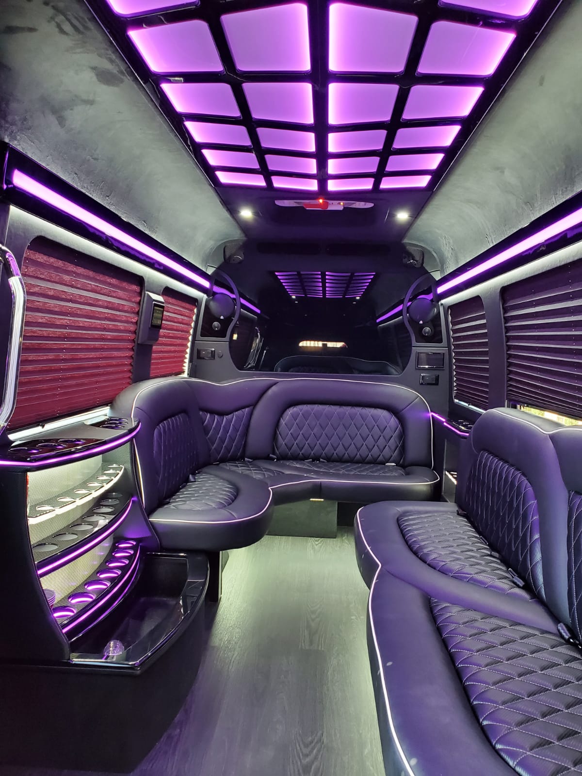 The inside of a purple limousine with purple lights on the ceiling.