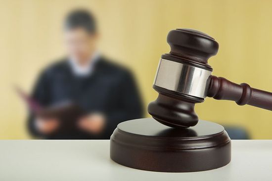 Un martello di giustizia e dietro una persona scialba