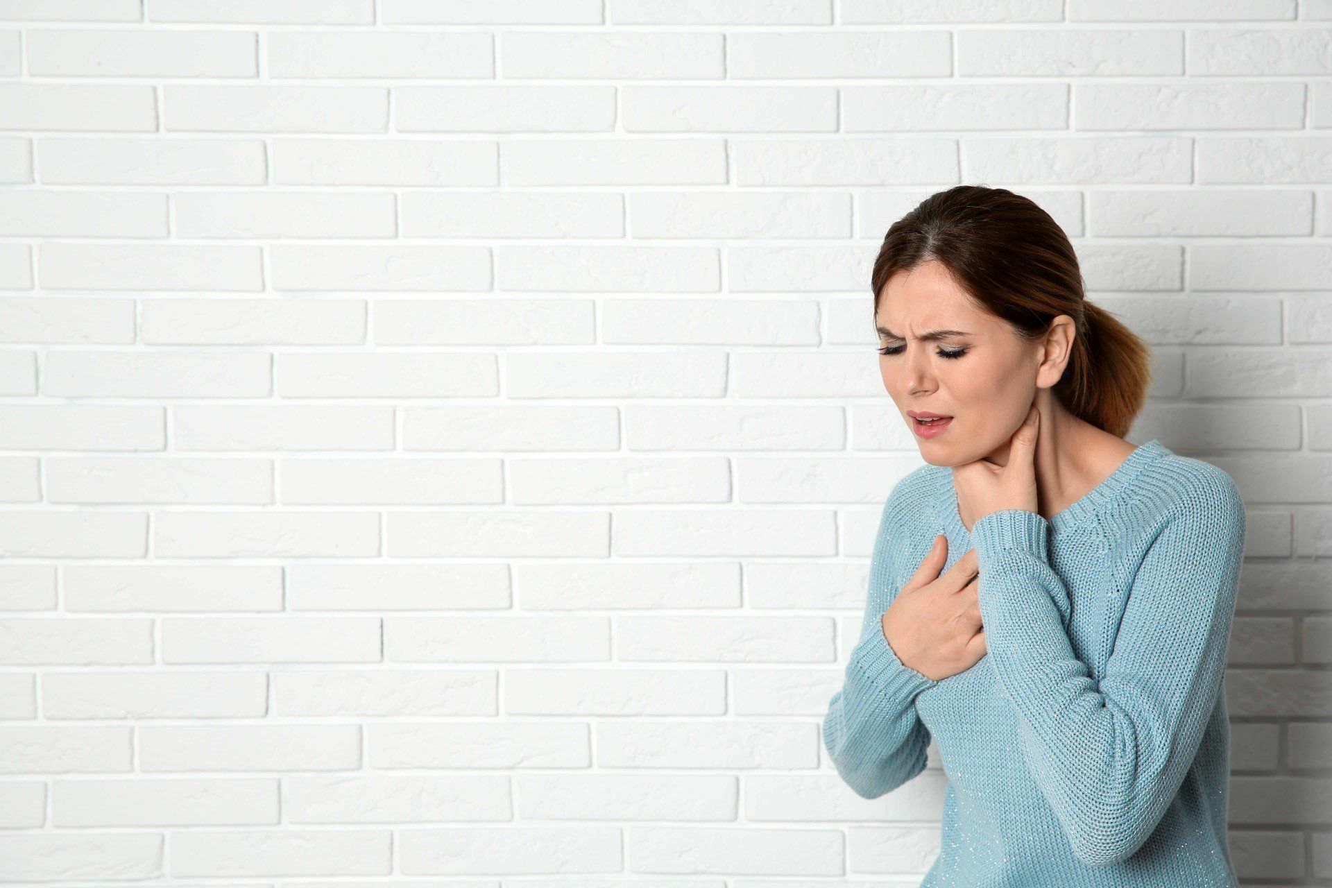 woman touching her chest after coughing