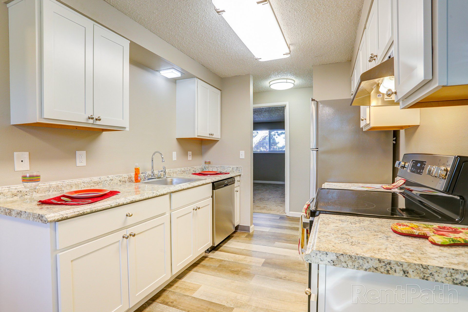 A kitchen with white cabinets , granite counter tops , stainless steel appliances and a sink.