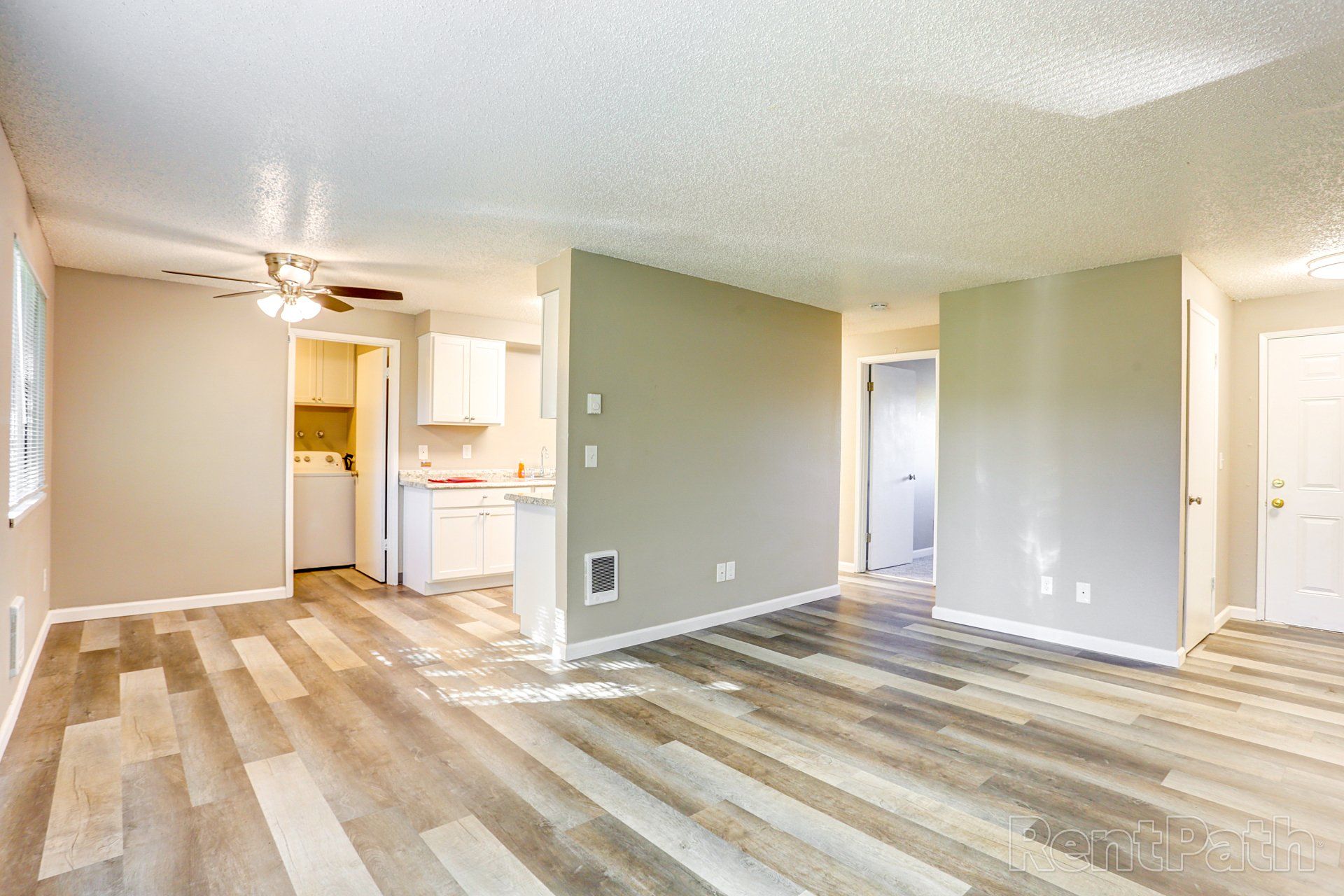 An empty living room with hardwood floors and a ceiling fan.