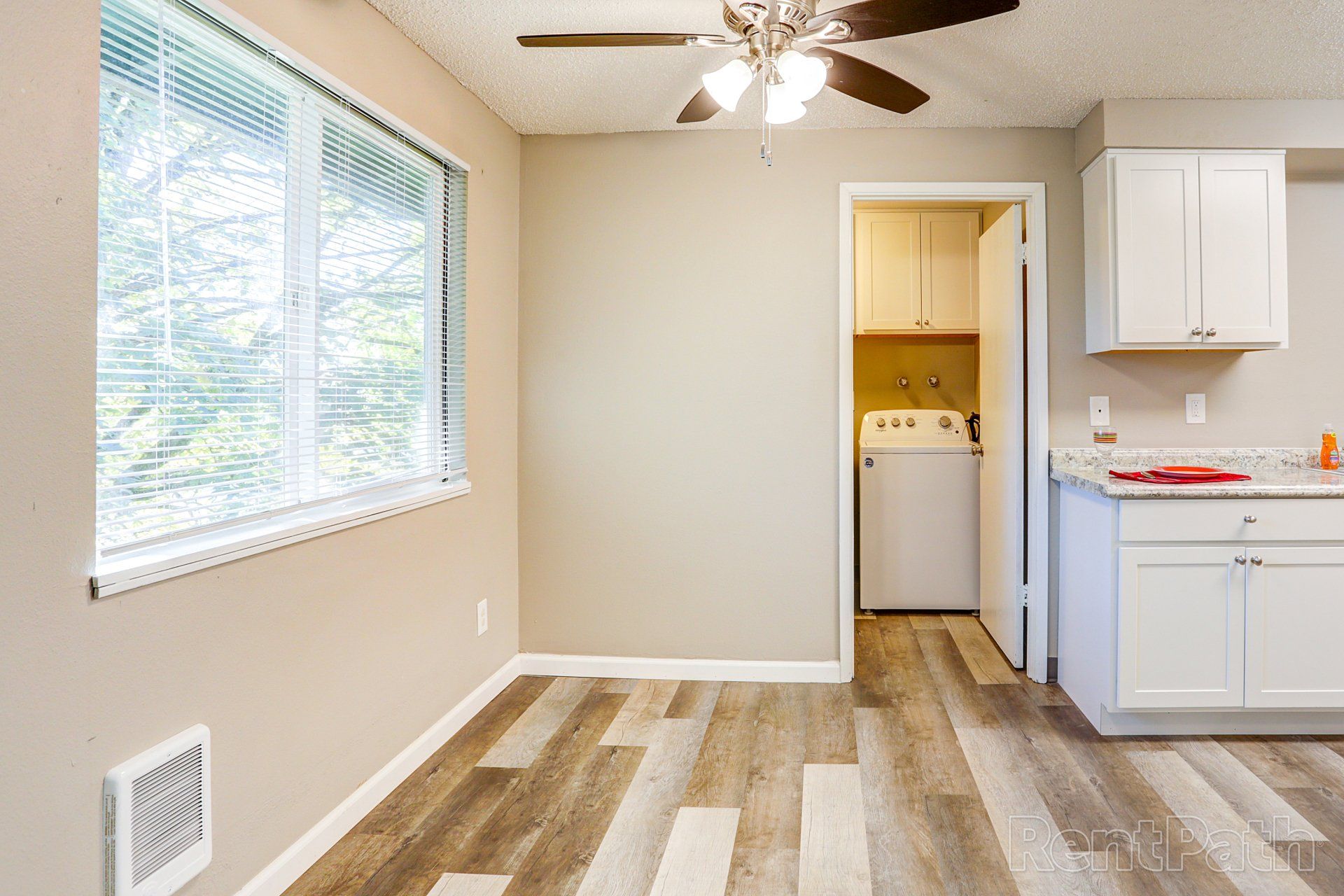An empty kitchen with a ceiling fan and a washer and dryer.