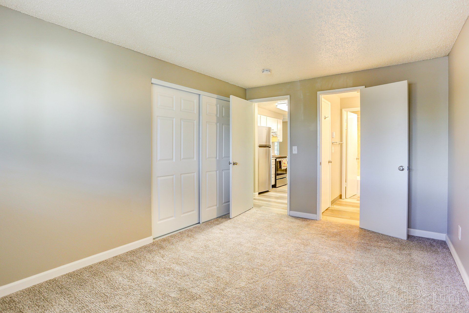 An empty bedroom with a carpeted floor and a closet.