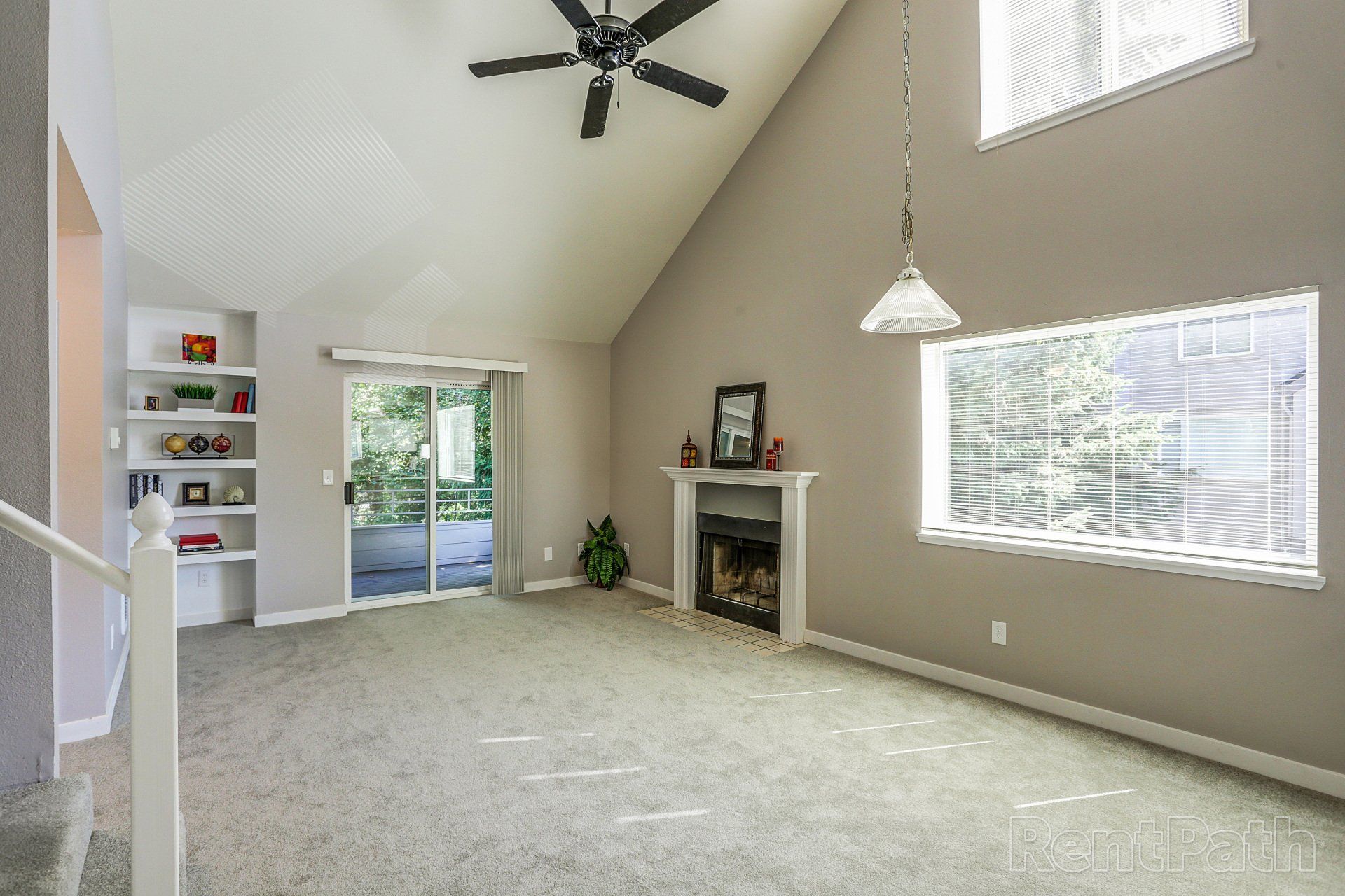 A living room with a fireplace and a ceiling fan.