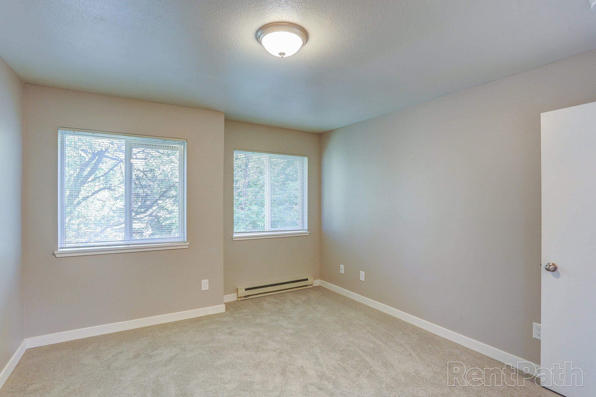 An empty bedroom with two windows and a ceiling light.