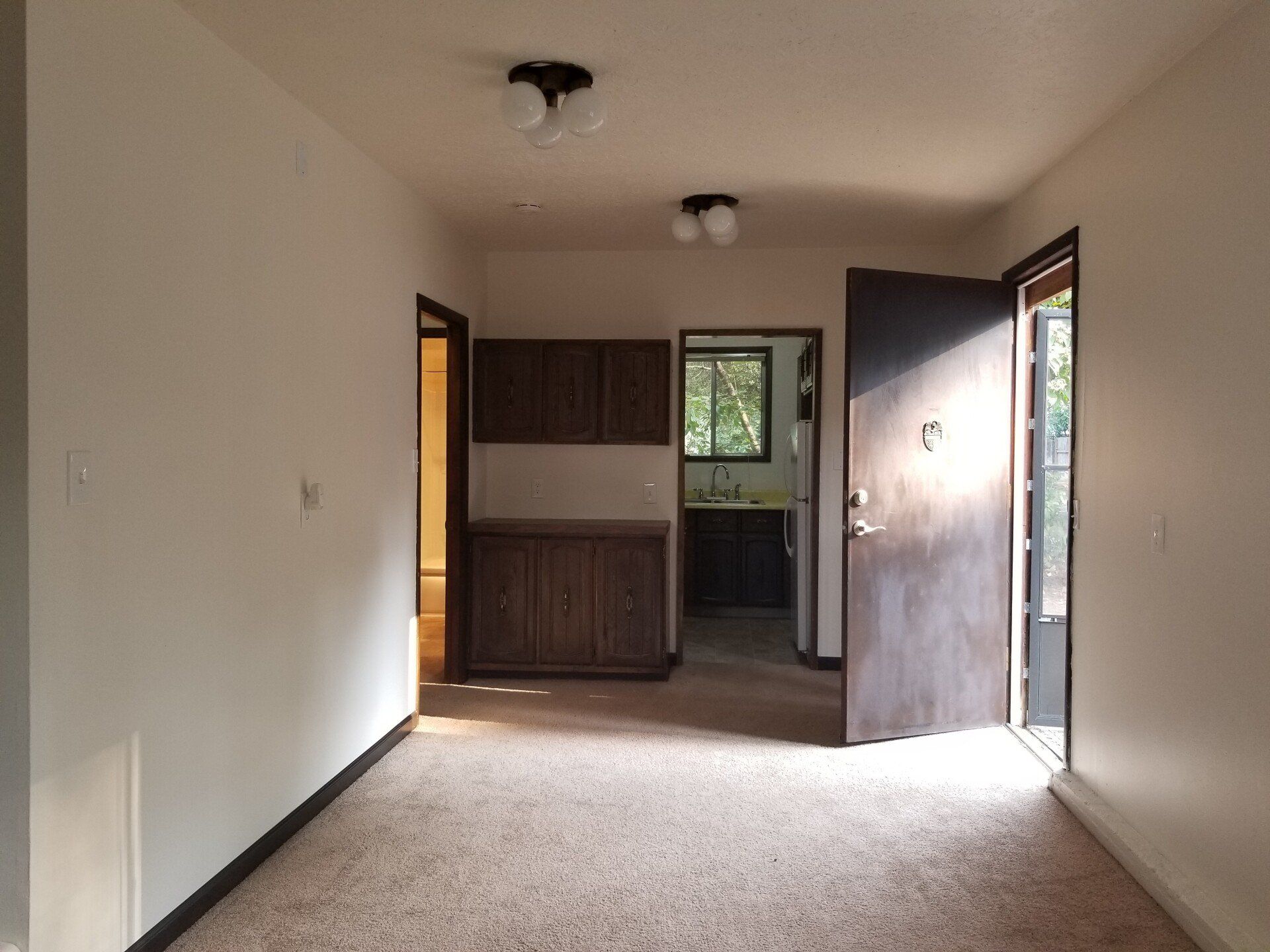 An empty room with a carpeted floor and white walls