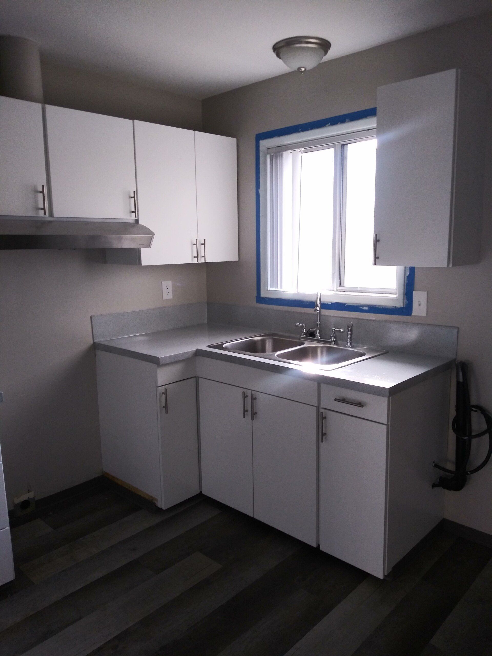 A kitchen with white cabinets a sink and a window