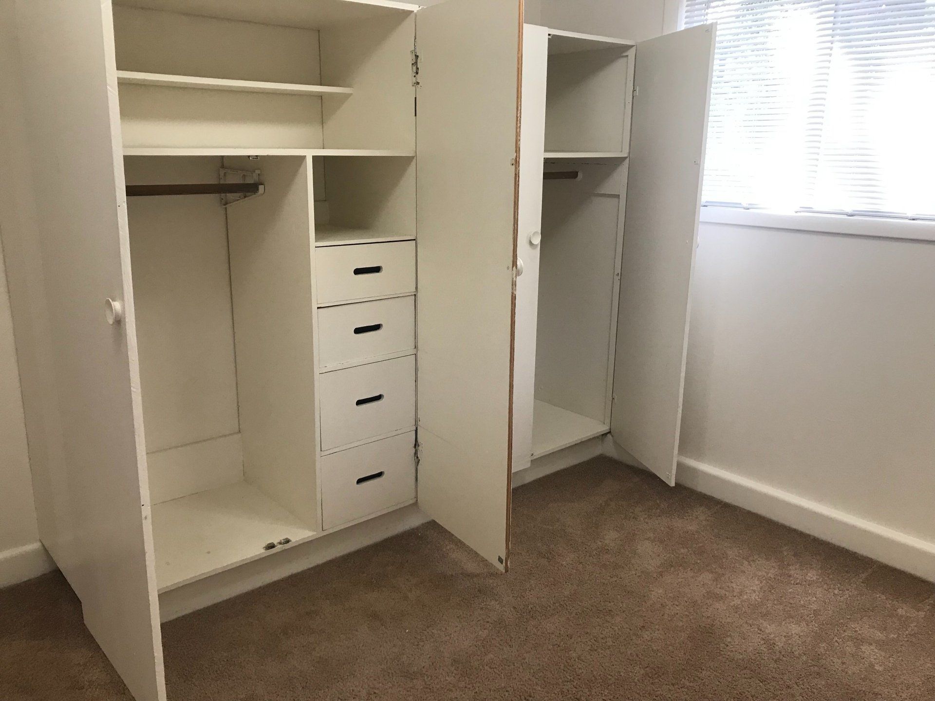 A bedroom with two white closets and a window.