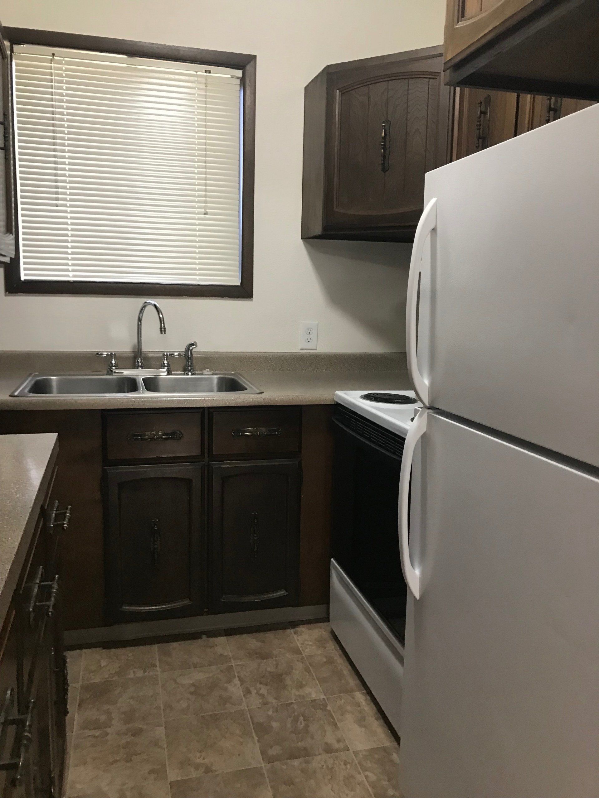 A kitchen with two sinks a stove and a refrigerator