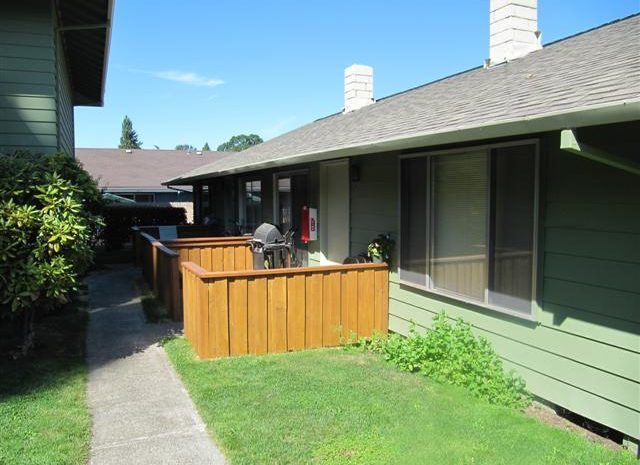 A green house with a wooden deck in front of it