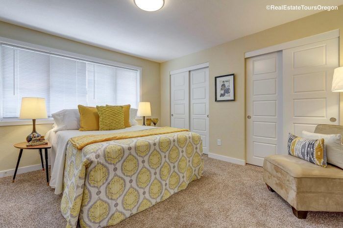 A bedroom with a bed , chair , lamps and a window.