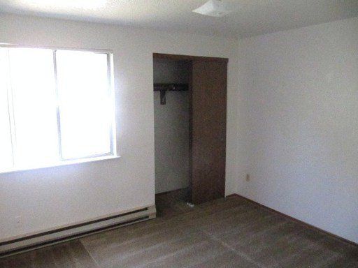 An empty bedroom with a closet and a window.