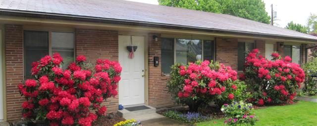 A brick house with red flowers in front of it