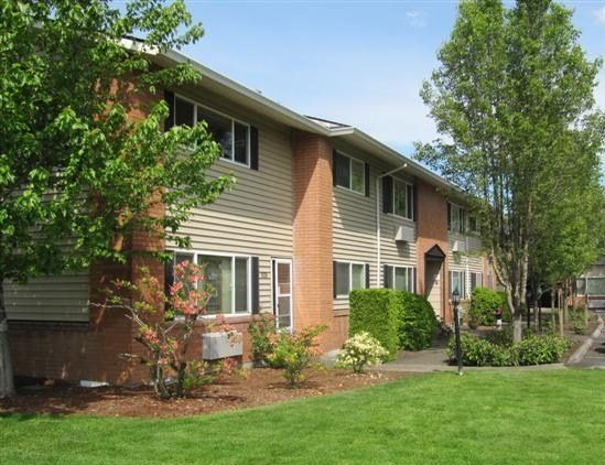 A large apartment building with a lush green lawn in front of it