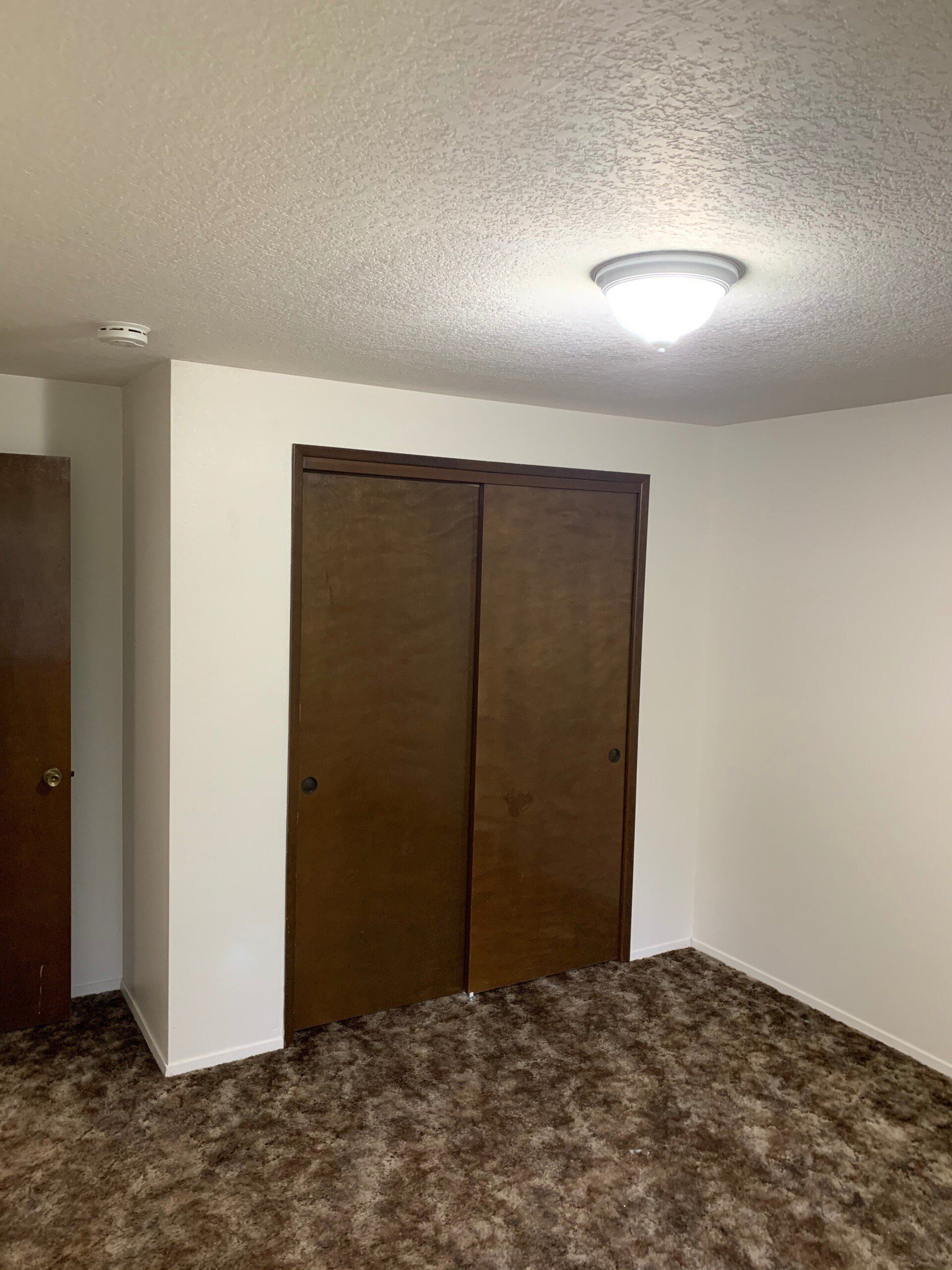 An empty bedroom with a closet and a light on the ceiling.