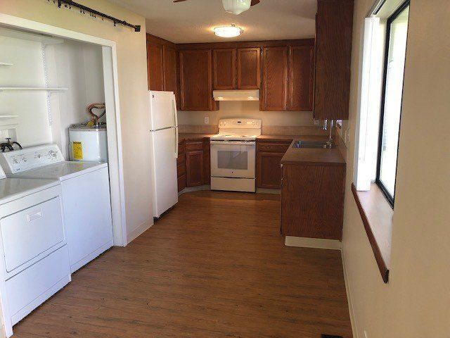 A kitchen with a stove , refrigerator , washer and dryer