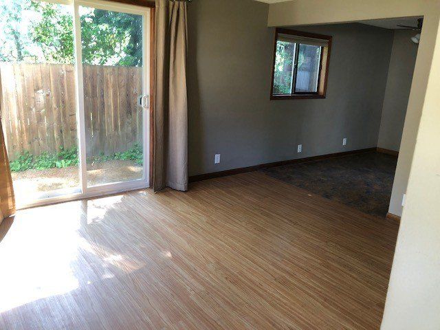 An empty living room with hardwood floors and a sliding glass door