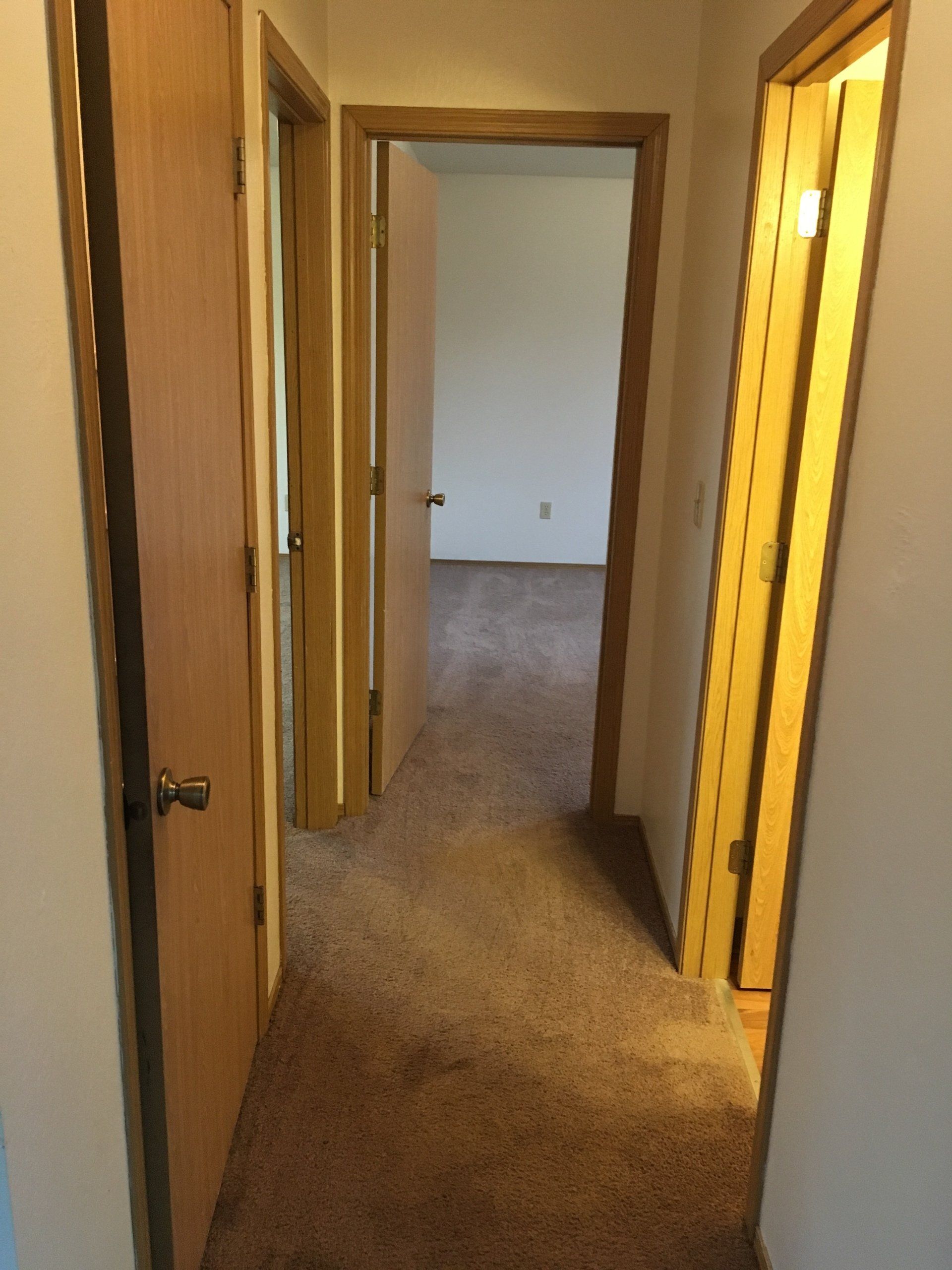 A hallway leading to a bedroom and a bathroom