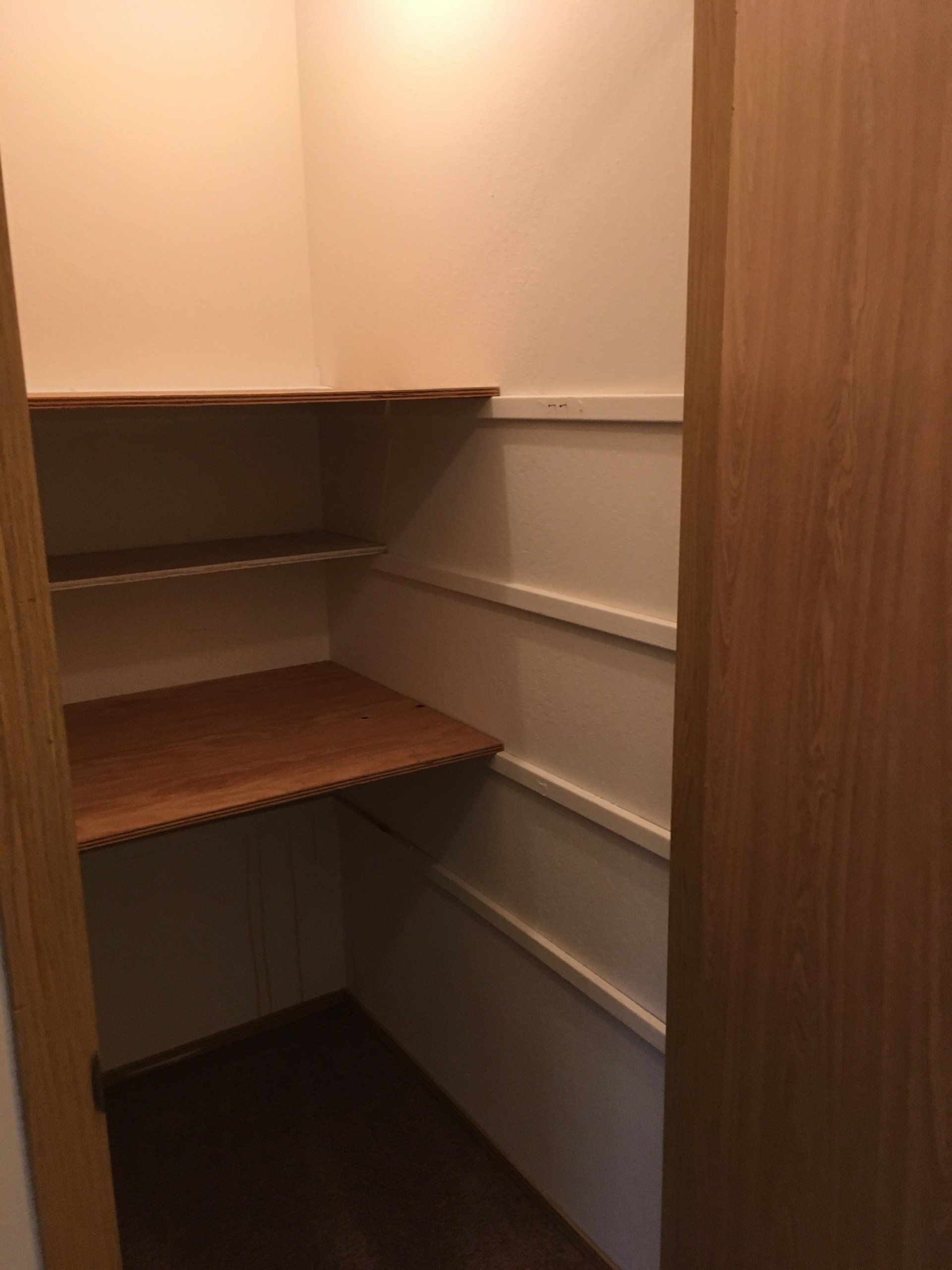 A small closet with wooden shelves and drawers.
