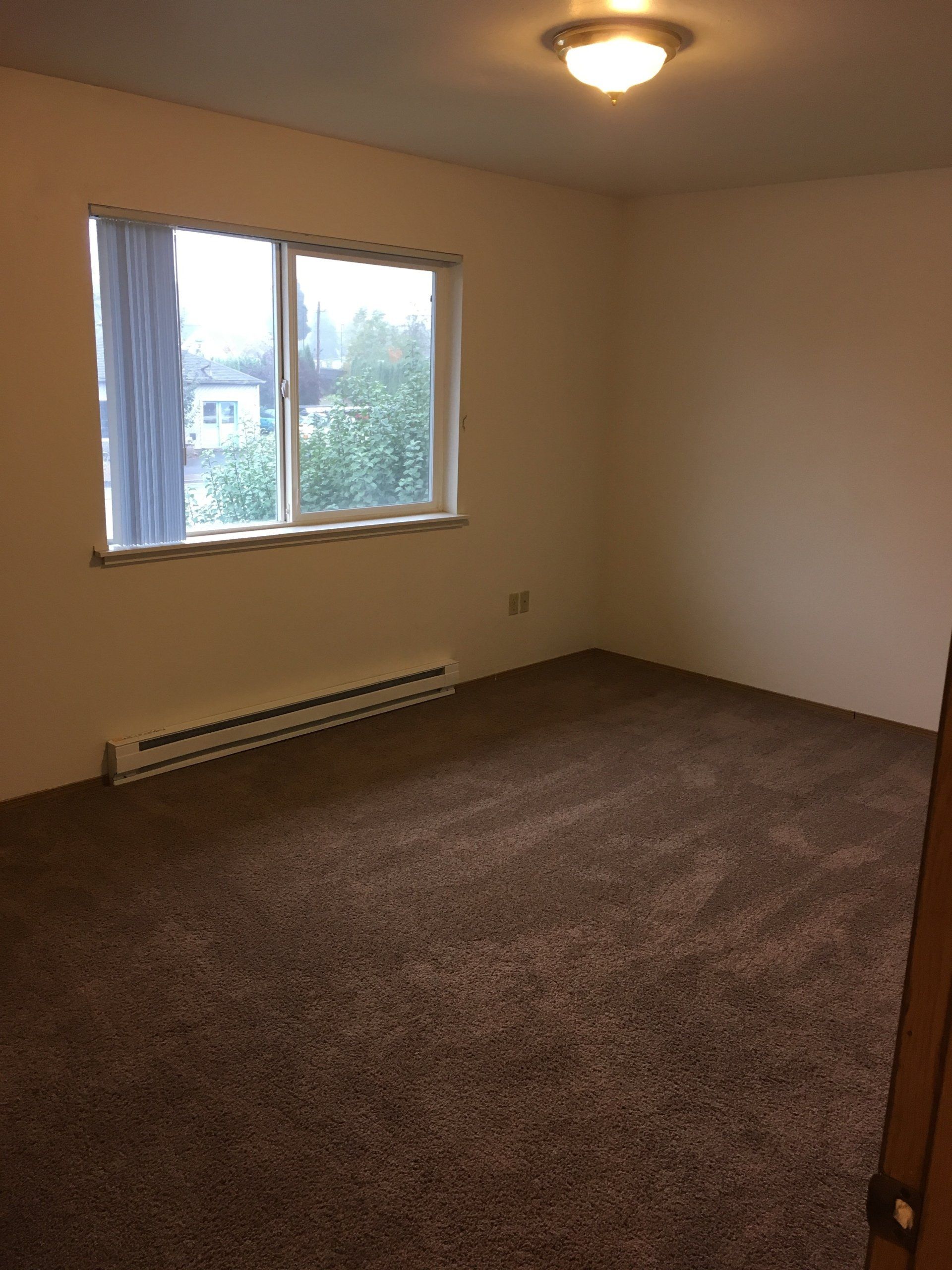 An empty room with a carpeted floor and a window.