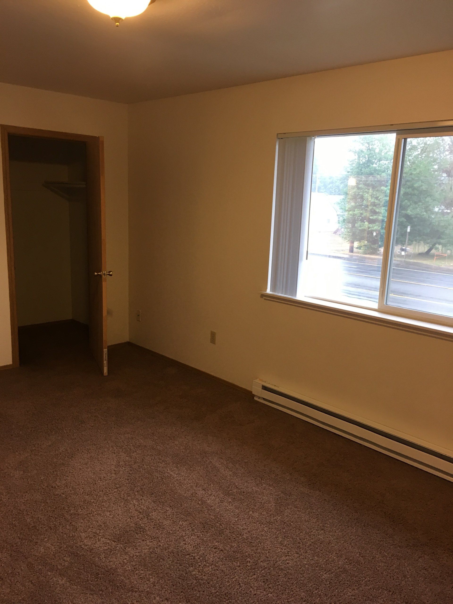 An empty room with a window and a carpeted floor