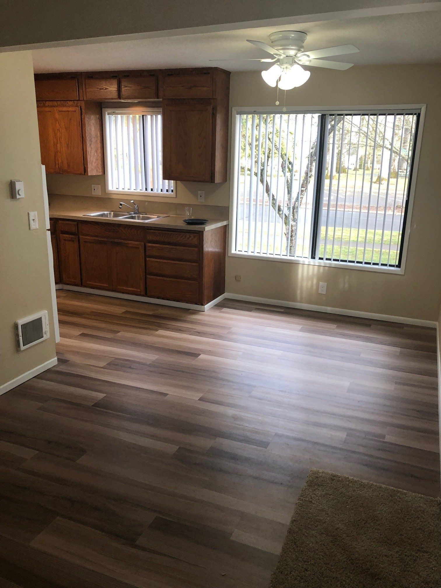 A kitchen with wooden cabinets , a sink , and a ceiling fan.